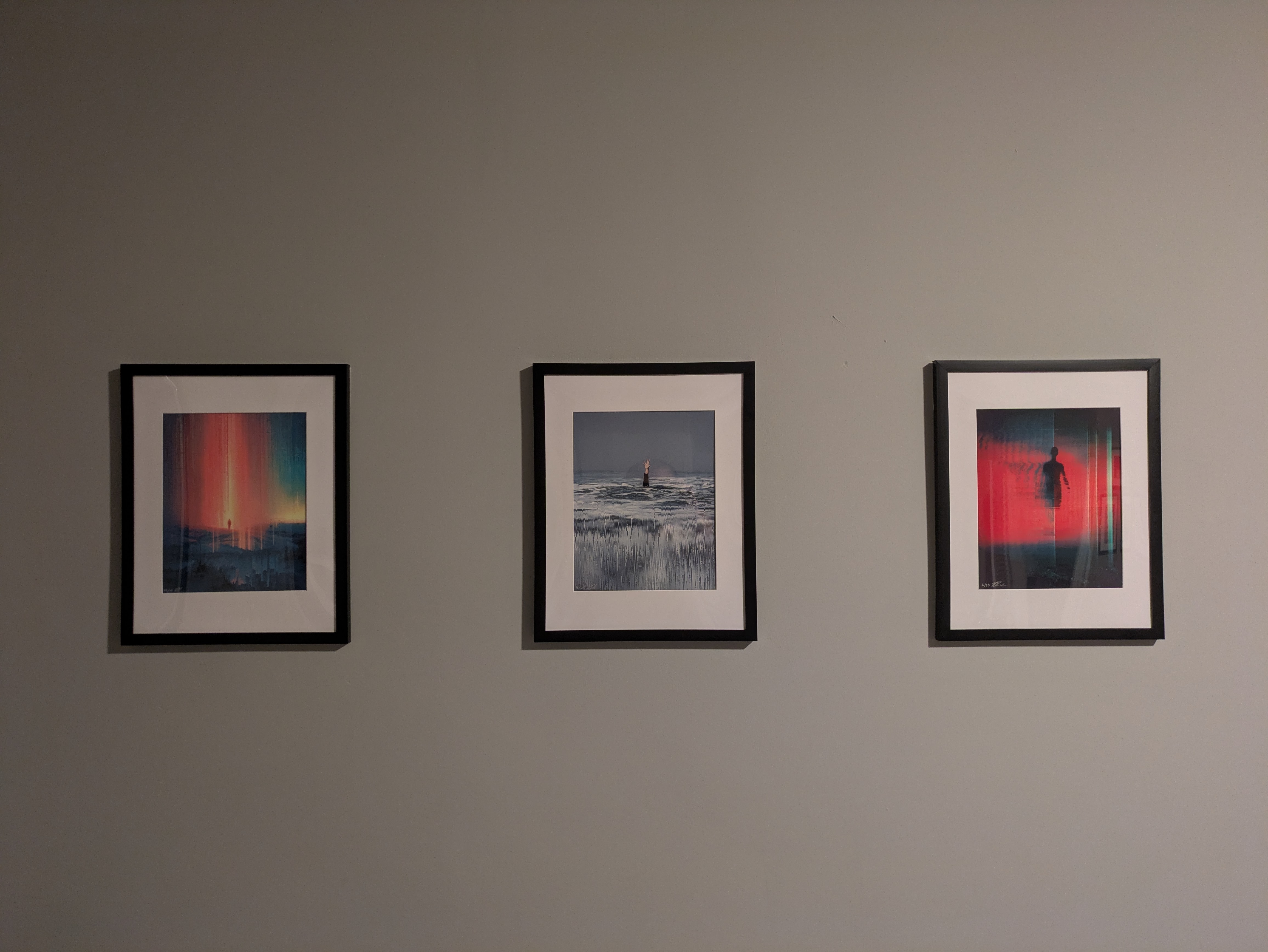 Three prints of Rob Sheridan's work framed on the wall: 'Precipice', 'Reach', and 'Turbulence' from left to right