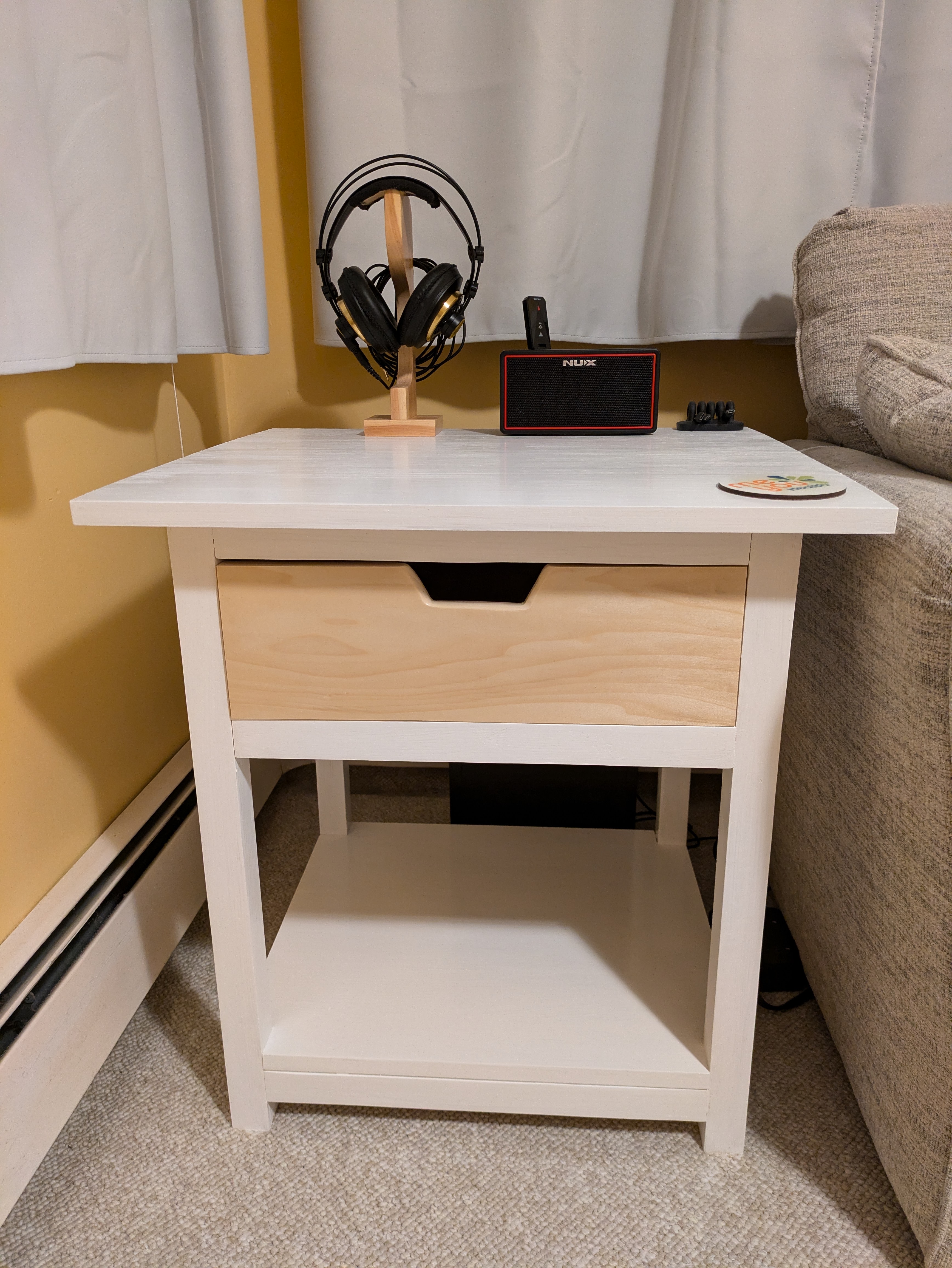 The completed table next to a couch with headphones and a speaker on top of it