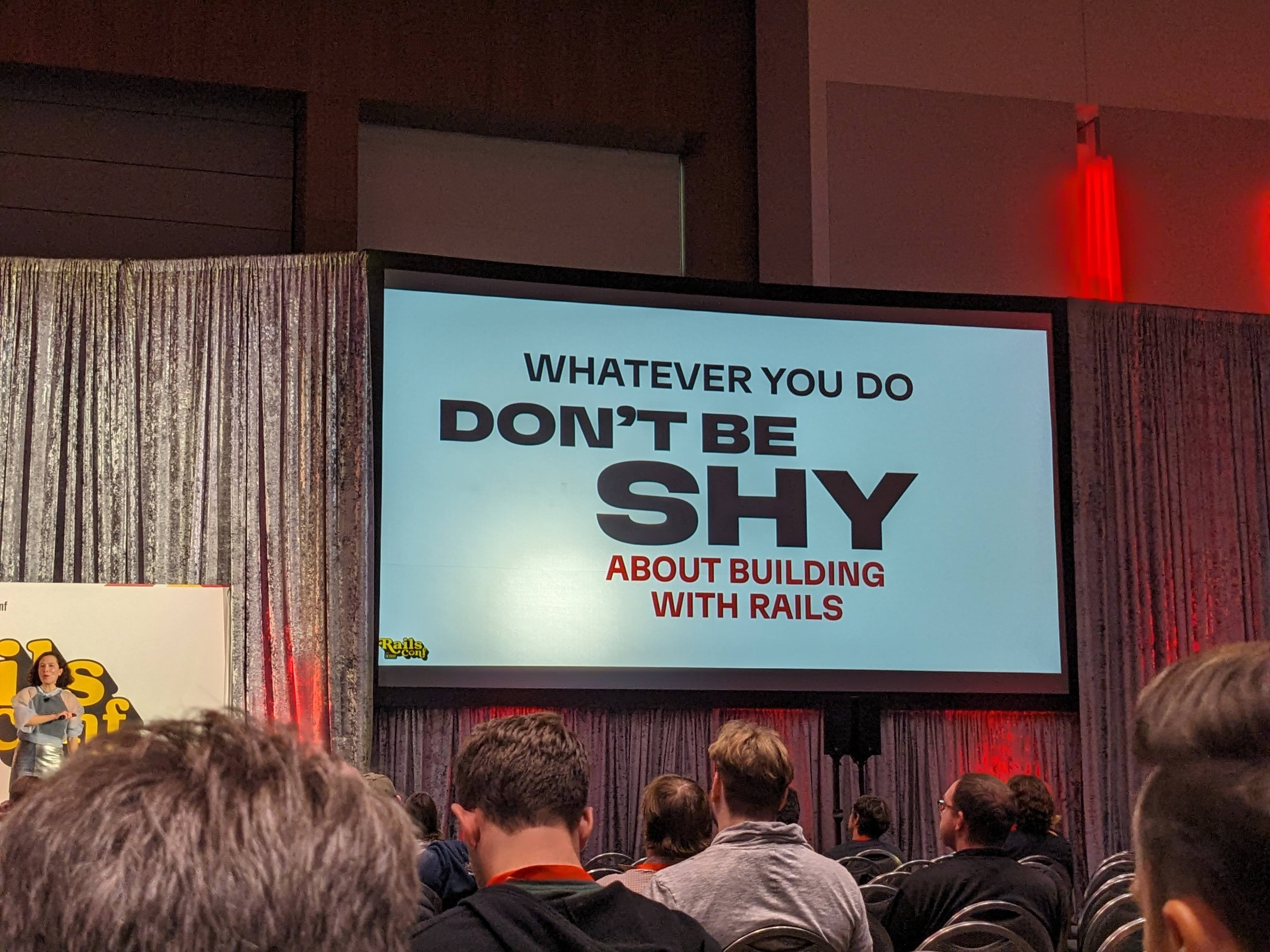 Irina at RailsConf 2024 with a slide that says, 'Whatever you do don't be shy about building with Rails'